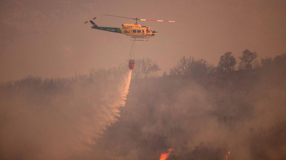 Ein Helikopter wirft Wasser über das Feuer in der Sierra de Mijas