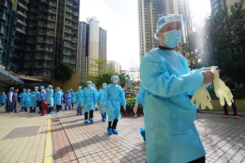 Mehrere Chinesen in Schutzanzügen und mit Faceshield