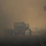 Feuerwehrleute stehen bei Löscharbeiten auf einer Straße in Louchats, Region Gironde, im Südwesten Frankreichs mitten im Rauch