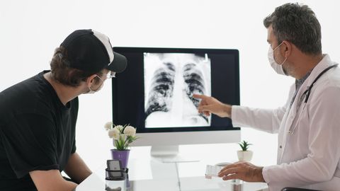 Arzt schaut mit Lungenkrebs-Patient auf eine Röntgenaufnahme der Brust
