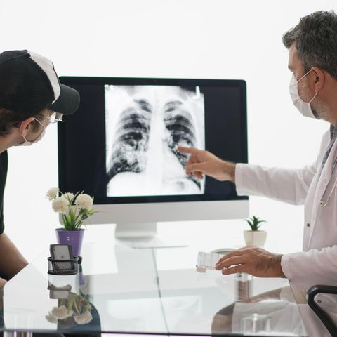 Arzt schaut mit Lungenkrebs-Patient auf eine Röntgenaufnahme der Brust