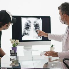 Arzt schaut mit Lungenkrebs-Patient auf eine Röntgenaufnahme der Brust