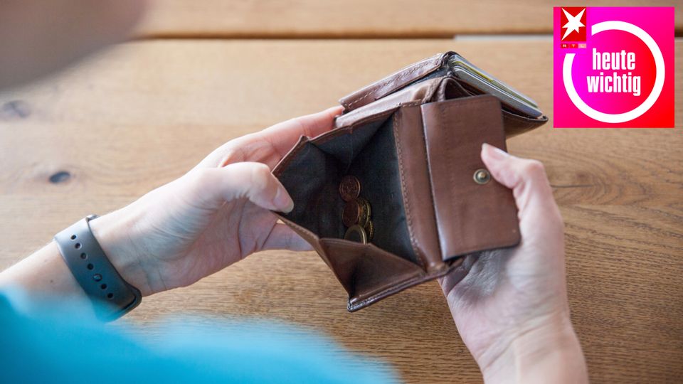 Eine ältere Frau schaut in eine Geldbörse mit ein paar Münzen darin