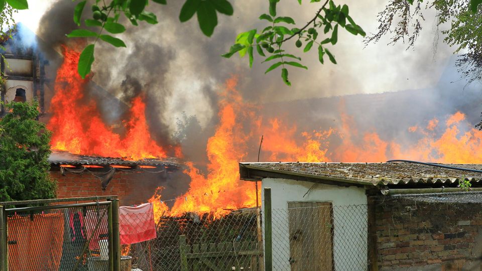Ein Haus und Nebengebäude stehen bei einem Brand in Flammen