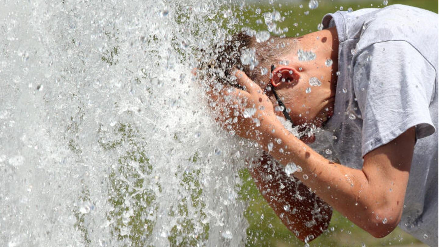 Hitze in Deutschland: Ein junger Mann erfrischt sich im Berliner Lustgarten am Wasser eines Brunnens.