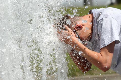 Hitze in Deutschland: Ein junger Mann erfrischt sich im Berliner Lustgarten am Wasser eines Brunnens.