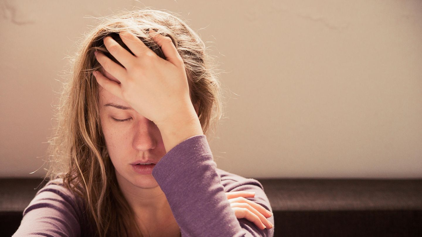 Eine Frau leidet unter psychosomatischen Beschwerden, wie Kopfschmerzen