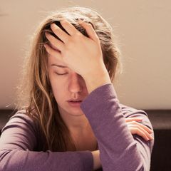 Eine Frau leidet unter psychosomatischen Beschwerden, wie Kopfschmerzen