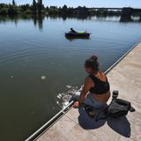 Am Main in Kitzingen, Bayern, gönnt sich eine Frau ein Fußbad, während ein junger Mann auf einer Luftmatratze entspannt