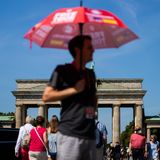 Vor dem Brandenburger Tor in Berlin nutzt dieser Mann einen Sonnenschirm, um einen einigermaßen kühlen Kopf zu bewahren