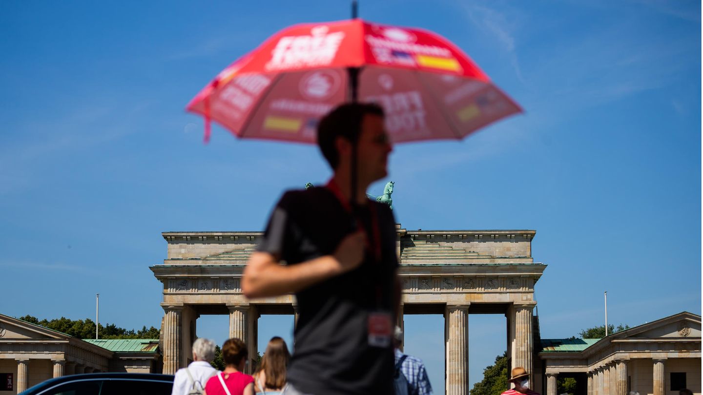 Vor dem Brandenburger Tor in Berlin nutzt dieser Mann einen Sonnenschirm, um einen einigermaßen kühlen Kopf zu bewahren