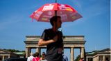 Vor dem Brandenburger Tor in Berlin nutzt dieser Mann einen Sonnenschirm, um einen einigermaßen kühlen Kopf zu bewahren