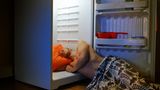 Mann liegt im Kühlschrank