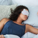 Frau liegt mit Schlafmaske im Bett