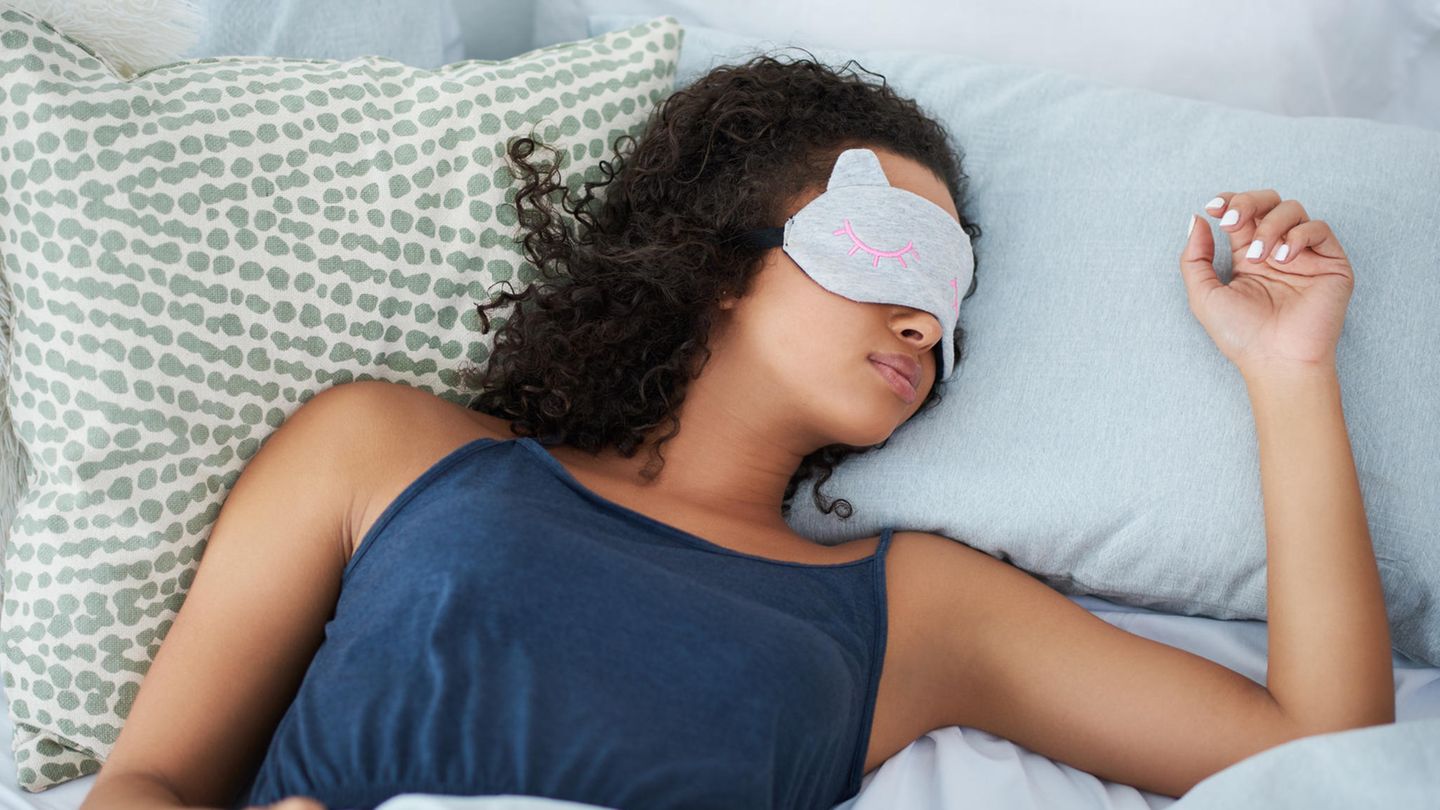 Frau liegt mit Schlafmaske im Bett