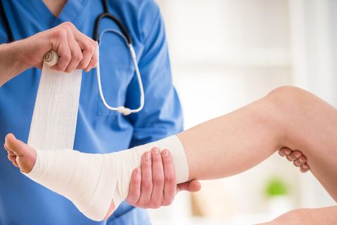 Eine Ärztin verbindet einer Patientin den Fuß