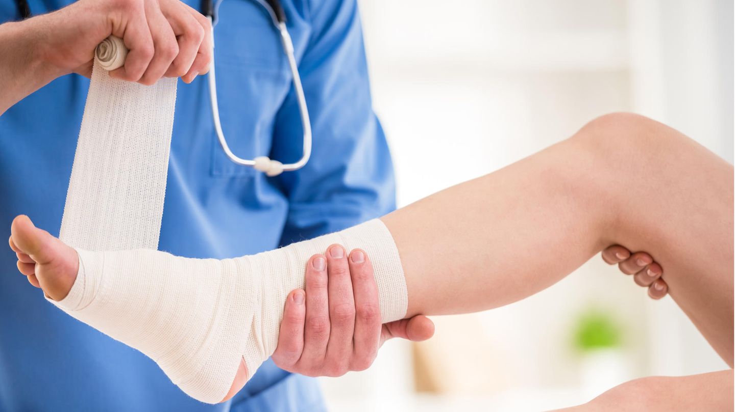Eine Ärztin verbindet einer Patientin den Fuß