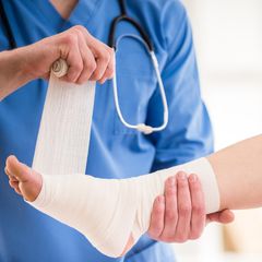 Eine Ärztin verbindet einer Patientin den Fuß