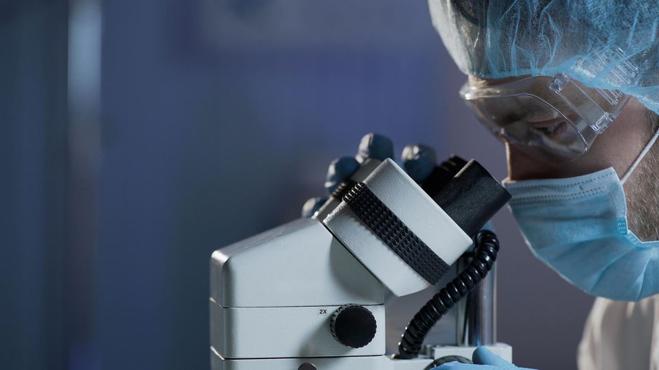 Ein Forscher sieht durch ein Mikroskop