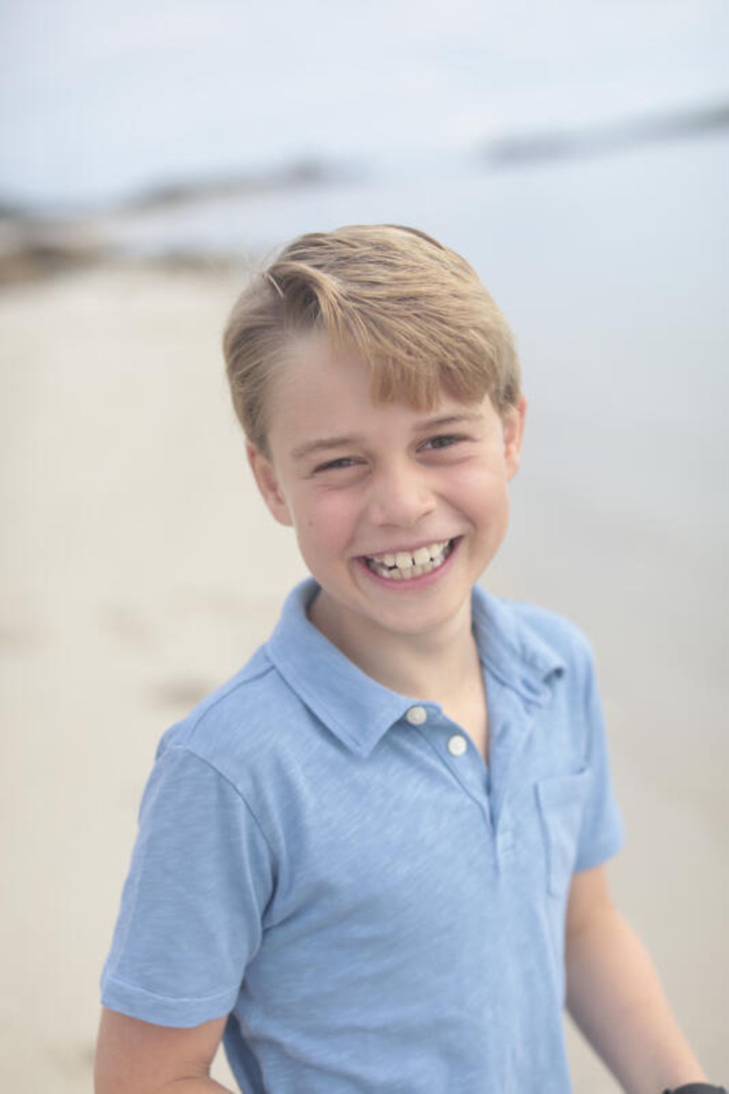 Prinz George lacht am Strand in die Kamera