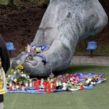 Blumen und Kerzen an der Bronzestatue von Uwe Seelers Fuß