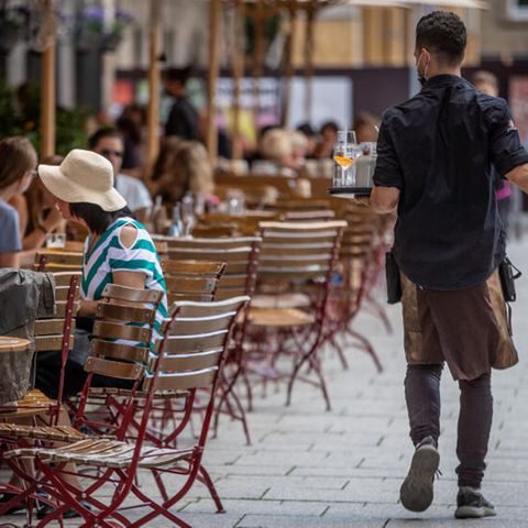 Ein Kellner bedient auf der Terrasse eines Restaurants