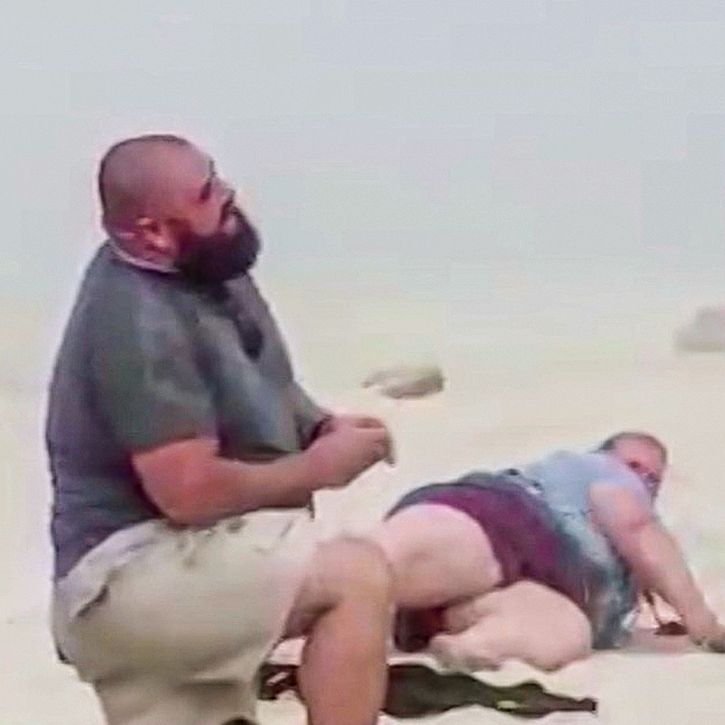 Ein Mann macht einer Frau einen Heiratsantrag am Strand – ihre Schwester stürzt im Hintergrund.