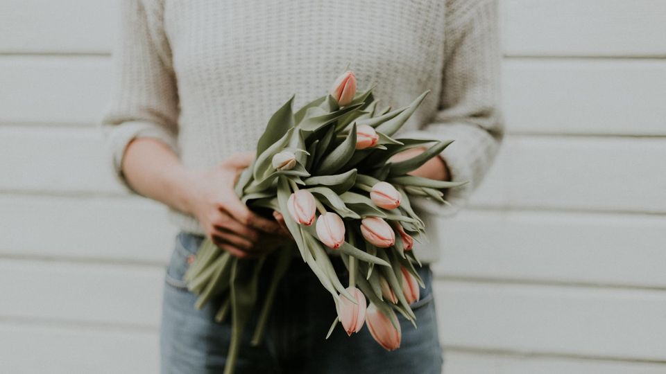 Eine Frau hält einen Strauß Tulpen in der Hand.