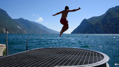 Ein junger Mann springt in den Gardasee