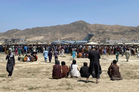 FILE- Hundreds of people gather near a U.S. Air Force C-17 transport plane at the perimeter of the international airport in Kabul, Afghanistan, Monday, Aug. 16, 2021. Afghanistan is the unhappiest country in the world â€” even before the Taliban swept t...