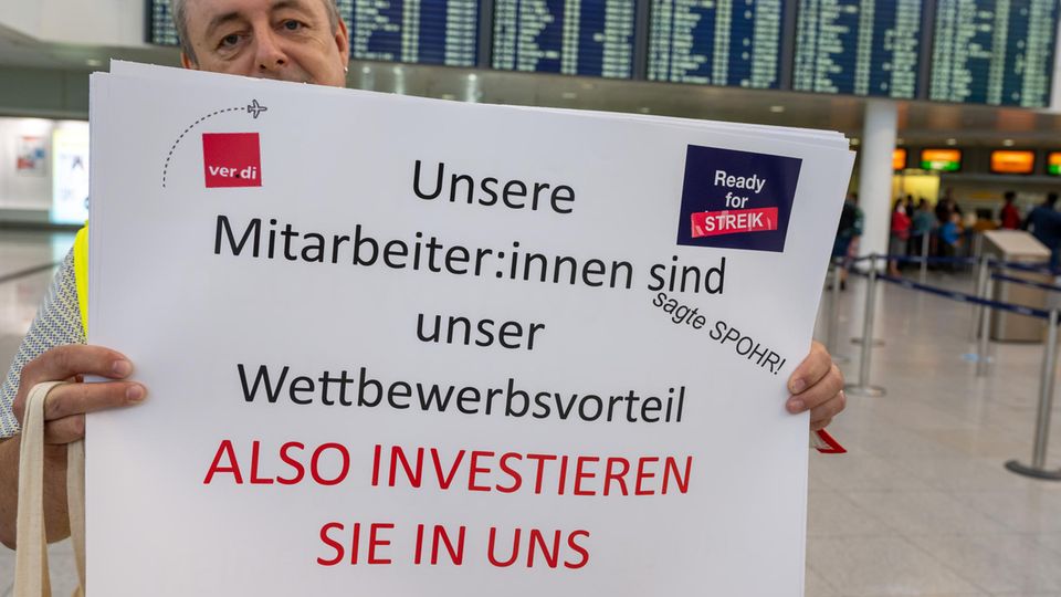 Ein Verdi-Mitarbeiter hält am Flughafen München ein Plakat hoch
