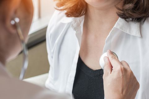Eine Ärztin hört eine Patientin mit dem Stethoskop ab