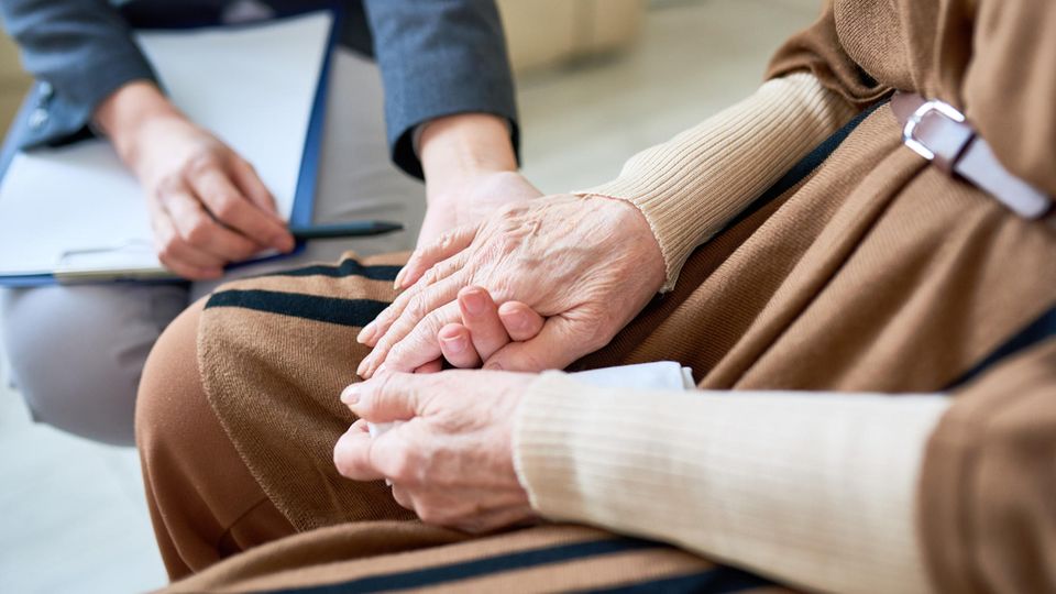 Trauer Trauerbewältigung Trost Ein Mann hält die Hand einer älteren Frau
