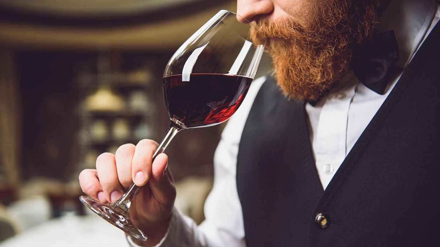 Mann riecht an einem Glas mit Rotwein