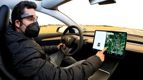 Ein Mann sitzt am Steuer eines Tesla-Autos und bedient den Touchscreen
