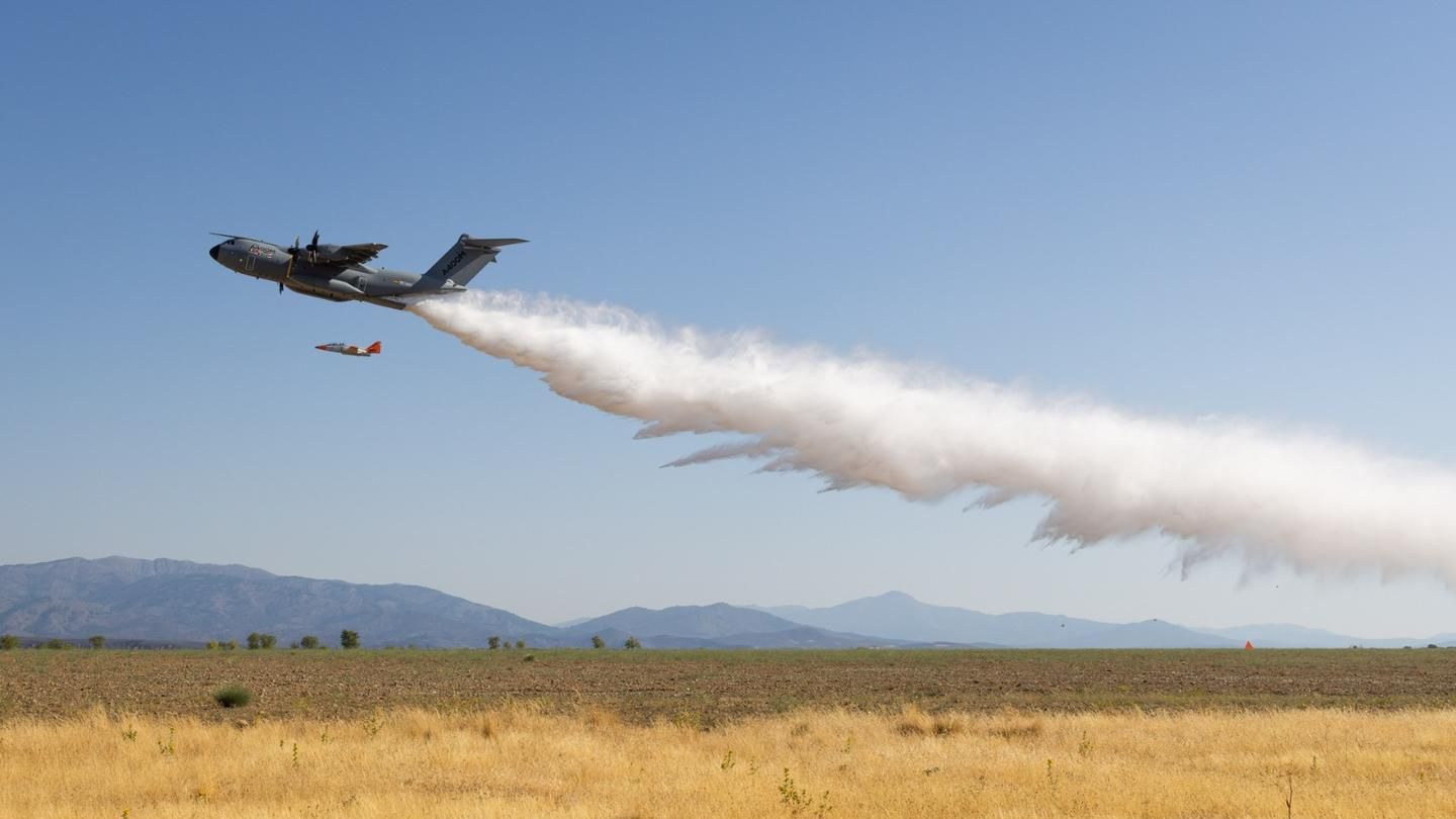 Ein Löschflugzeug wirft Wasser über einem Feld ab