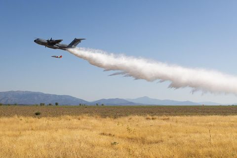Ein Löschflugzeug wirft Wasser über einem Feld ab