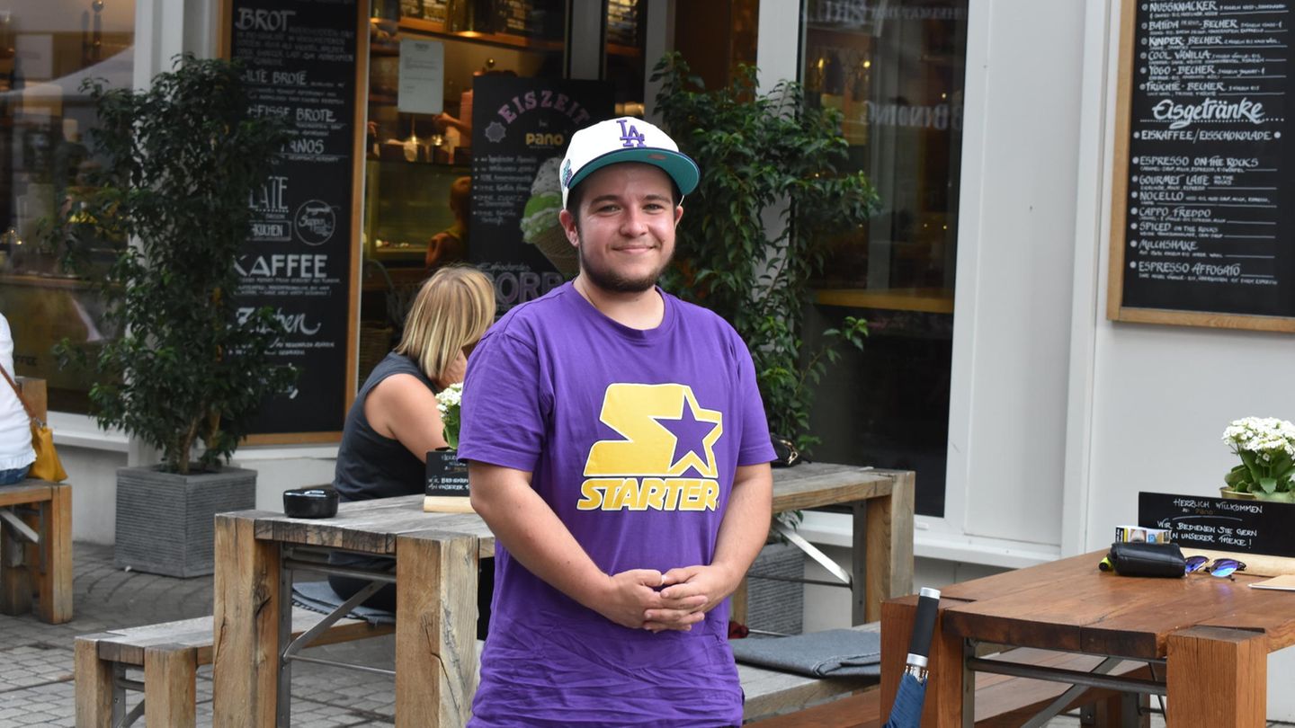 Sebastian steht auf der Straße vor einem Café