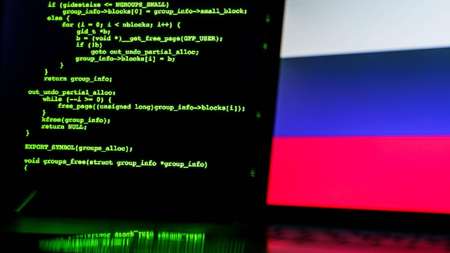 Ein Bildschirm mit grüner Schrift, dahinter die russische Flagge