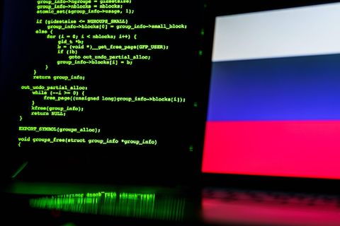 Ein Bildschirm mit grüner Schrift, dahinter die russische Flagge