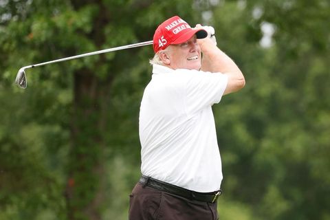 Donald Trump in weißem Hemd und roter Schirmmütze schwingt den Golfschläger beim Abschlag