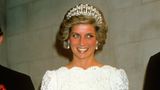 Die Queen Mary's Lover's Knot Tiara  Die Geschichte der Queen Mary's Lover's Knot begann bereits im Jahr 1818. Da bekam sie Prinzessin Auguste von Hessen geschenkt. Sie vererbte das Stück ihrer Tochter und so ist die Tiara heute noch im Besitz des Hauses Mecklenburg-Strelitz. 1913 gab Augustes Enkelin, Queen Mary, eine sehr ähnliche Tiara beim Hof-Juwelier Garrard in Auftrag. Zwischen den beiden Diademen gibt es mehrere Unterschiede. Angefangen beim Namen: Das deutsche Exemplar heißt Cambridge Lover's Knot Tiara, nach dem Titel, den Auguste im Zuge ihrer Hochzeit mit dem Herzog von Cambridge erhält. Währenddessen ist die Replik nach Queen Mary benannt. Außerdem verfügt die ältere Version über große Perlen über den Bögen, während bei der jüngeren große Diamanten angebracht sind. Queen Mary vererbte die Tiara ihrer Enkelin, der späteren Queen Elizabeth II. In ihrem Besitz ist das prunkvolle Stück bis zu ihrem Tod 2022. Jetzt gehört sie König Charles III. Zu denjenigen, die sich das Schmuckstück leihen durften, gehörte zum Beispiel Prinzessin Diana. Auf dem Foto trägt sie die Queen Mary's Lover's Knot Tiara im Jahr 1985 beim Staatsbesuch in den USA.
