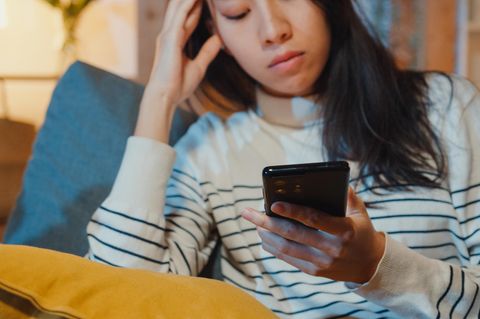 Frau schaut auf ihr Handy und nutzt Social Media