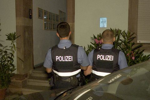 Polizeibeamte stehen vor einem Hauseingang