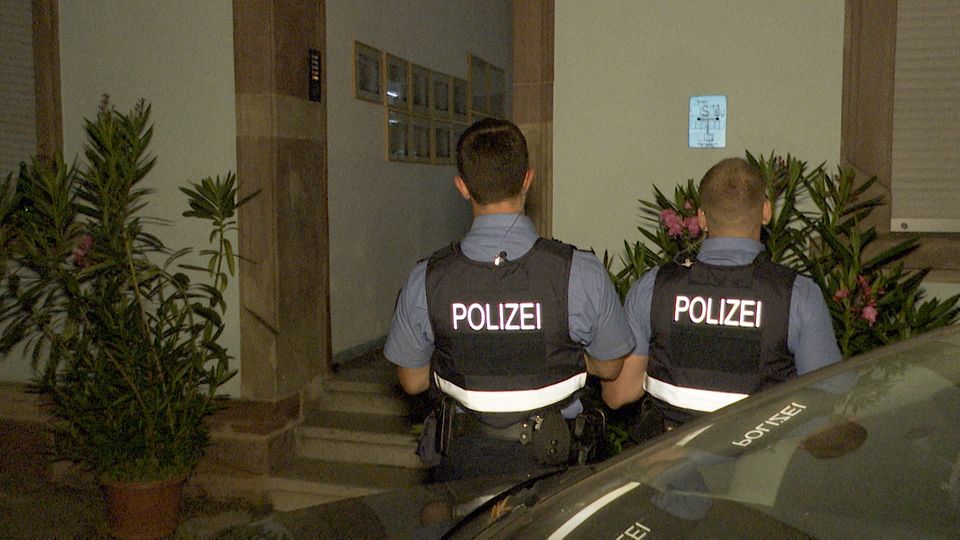 Polizeibeamte stehen vor einem Hauseingang