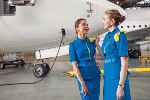 Zwei Flugbegleiterinnen stehen vor dem Flug vor einem Flugzeug
