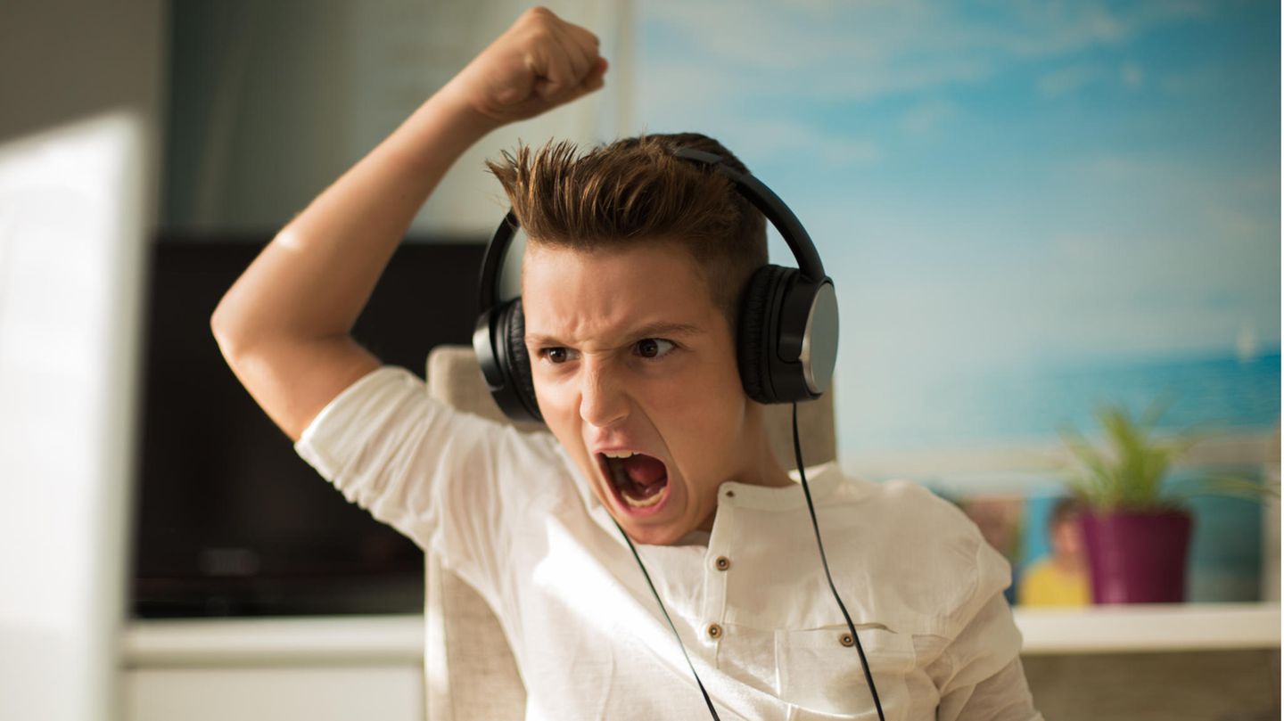 Ein Teenager sitzt am PC und freut sich
