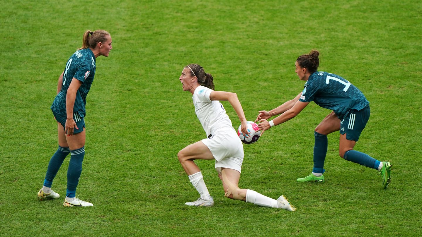 Eine weiße Fußballspielerin ganz in Weiß springt mit weit aufgerissenem Mund auf und nähert sich ihrer Gegenspielerin in Grün