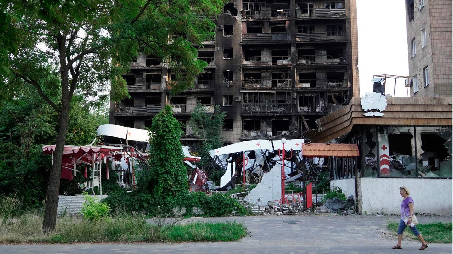 Frau geht an zerstörtem Wohnblock in Mariupol vorbei