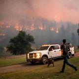 Ein Mann läuft zu einem Auto, während in Hintergrund das McKinney-Feuer im Klamath National Forest in Kalifornien wütet.